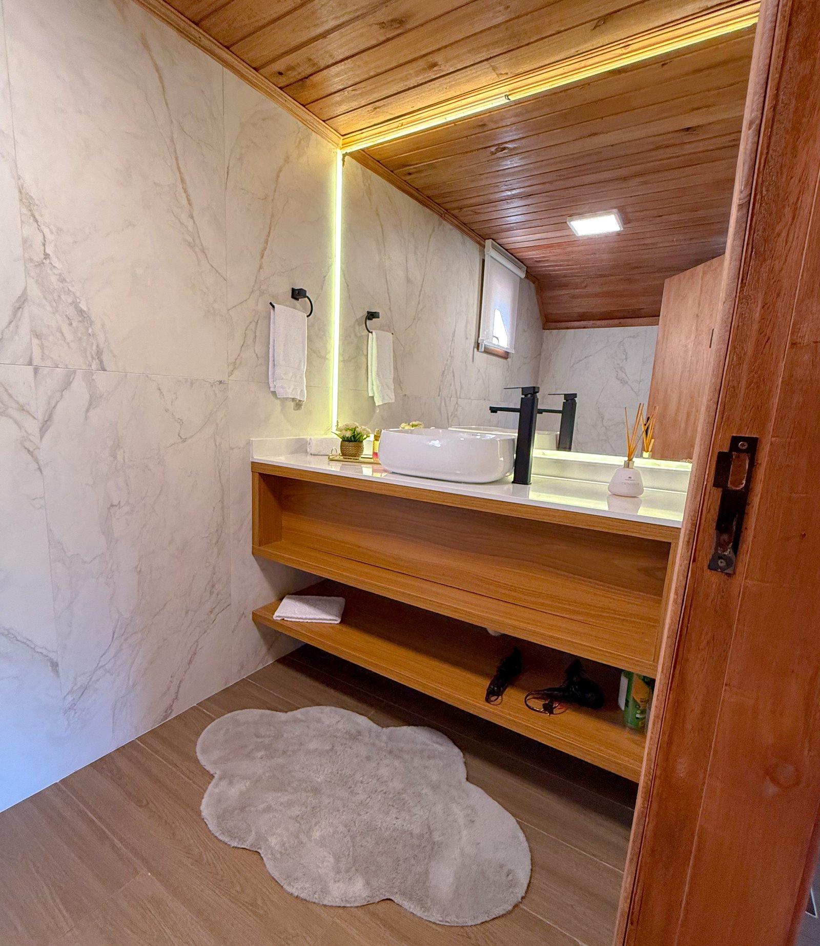 Banheiro da Cabana Miragem com bancada de madeira e cuba iluminada