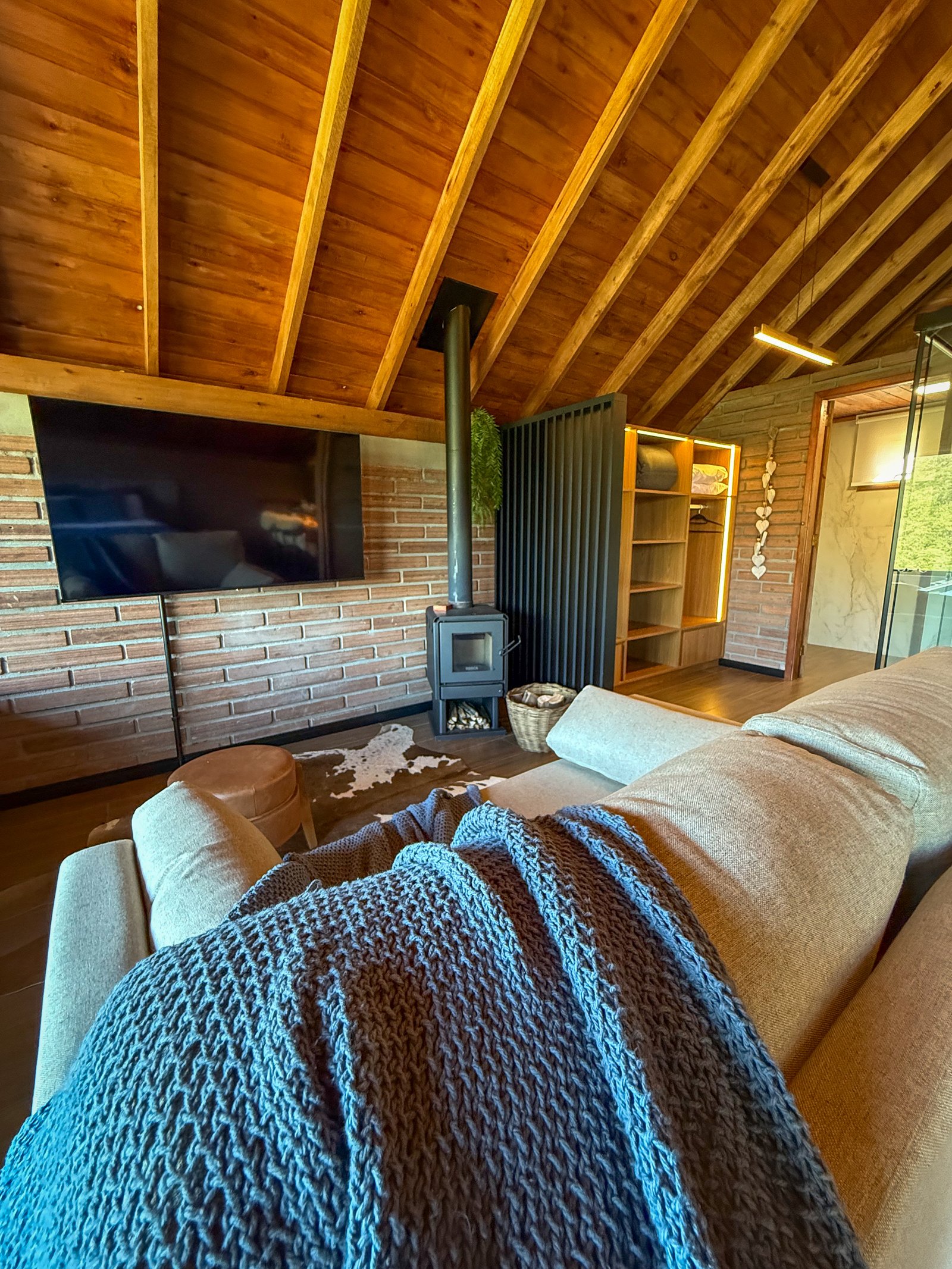 Sala da Cabana Miragem com lareira, sofá e acabamento em madeira